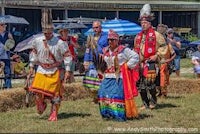 a group of people dressed in native clothing are walking in a field