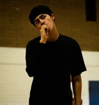 a man in a black shirt smoking a cigarette in a gym