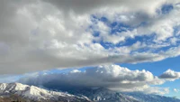 a cloudy sky with snow capped mountains in the background