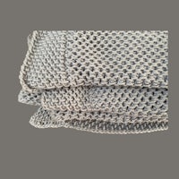 a stack of grey knitted blankets on a grey background