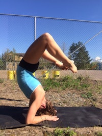 a woman doing a handstand on a black mat