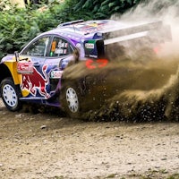 a red bull rally car driving through a forest