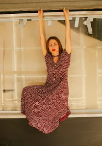 a woman in a polka dot dress hanging from a window