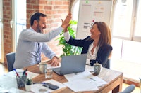 two business people giving each other high fives in an office