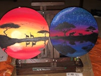 two paintings of giraffes and sunset on an easel