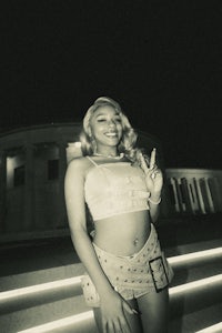 a black and white photo of a woman posing in front of a building