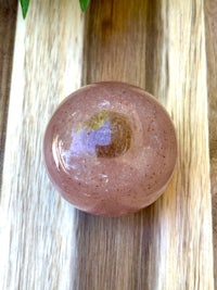 a pink stone sitting on top of a wooden cutting board