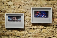 two framed pictures hanging on a stone wall