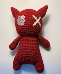 a red crocheted stuffed animal with a cross on it