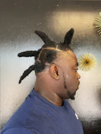 a man with dreadlocks in front of a wall