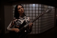 a woman holding a black electric guitar in a dark room