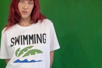 a woman wearing a white t - shirt that says swimming