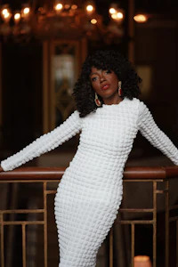 a woman in a white dress posing on a railing