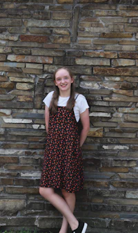 a girl is leaning against a stone wall
