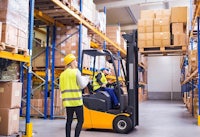 two people working in a warehouse with a forklift