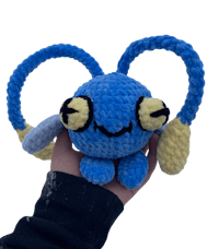 a blue crocheted toy with yellow and blue eyes