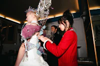 a woman is putting a dress on a woman