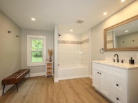 a white bathroom with wood floors and a sink