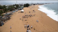 people are walking on a sandy beach near the ocean