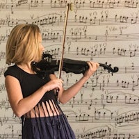 a young girl playing a violin in front of sheet music
