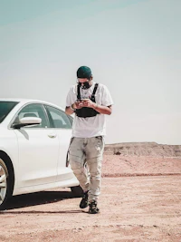 a man standing next to a white car in the desert