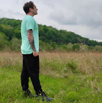 a man standing in a field with tattoos
