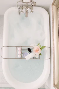 a bathroom with a tub filled with soap and flowers