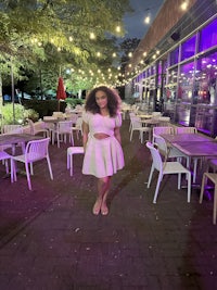 a woman in a white dress standing on a patio at night