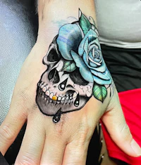 a woman's hand with a skull and rose tattoo