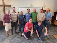 a group of men posing for a photo in a conference room