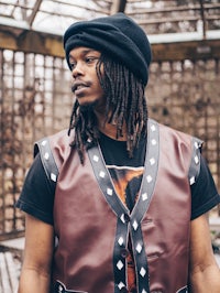 a man with dreadlocks wearing a leather vest