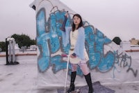 a woman standing on a roof with a skateboard