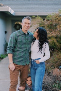 a man and woman standing in front of their home