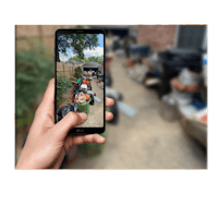 a person holding up a phone to take a picture of a backyard