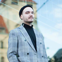 a man in a plaid jacket standing in front of a building