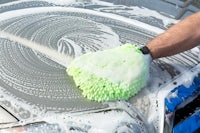 a man washing his car with a green sponge