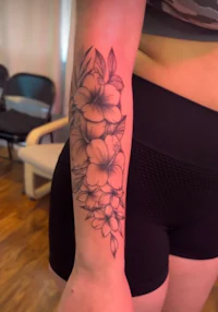 a black and white flower tattoo on a woman's forearm