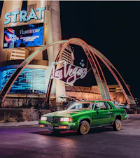 a green car parked in front of the las vegas sign