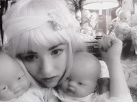 a woman holding two dolls in front of a mirror