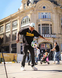 a man kicking a soccer ball in a city