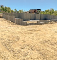 a concrete wall is being built in a dirt field