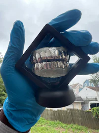 a person holding up a silver gummy grin in a blue glove
