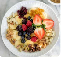a bowl of fruit, nuts, and berries