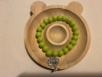 a green beaded bracelet with a teddy bear on it