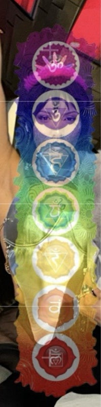 a woman is standing in front of an image of the seven chakras