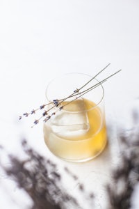 a glass of lemonade with lavender sprigs and ice