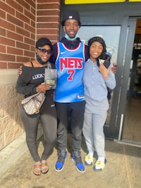 three people posing for a picture in front of a nba store