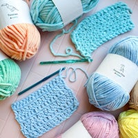 a variety of yarns and knitting needles are laid out on a table