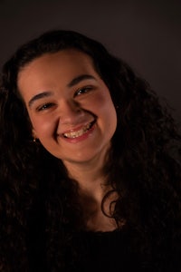 a young woman with curly hair smiling for the camera
