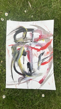 an abstract painting on a piece of paper in the grass